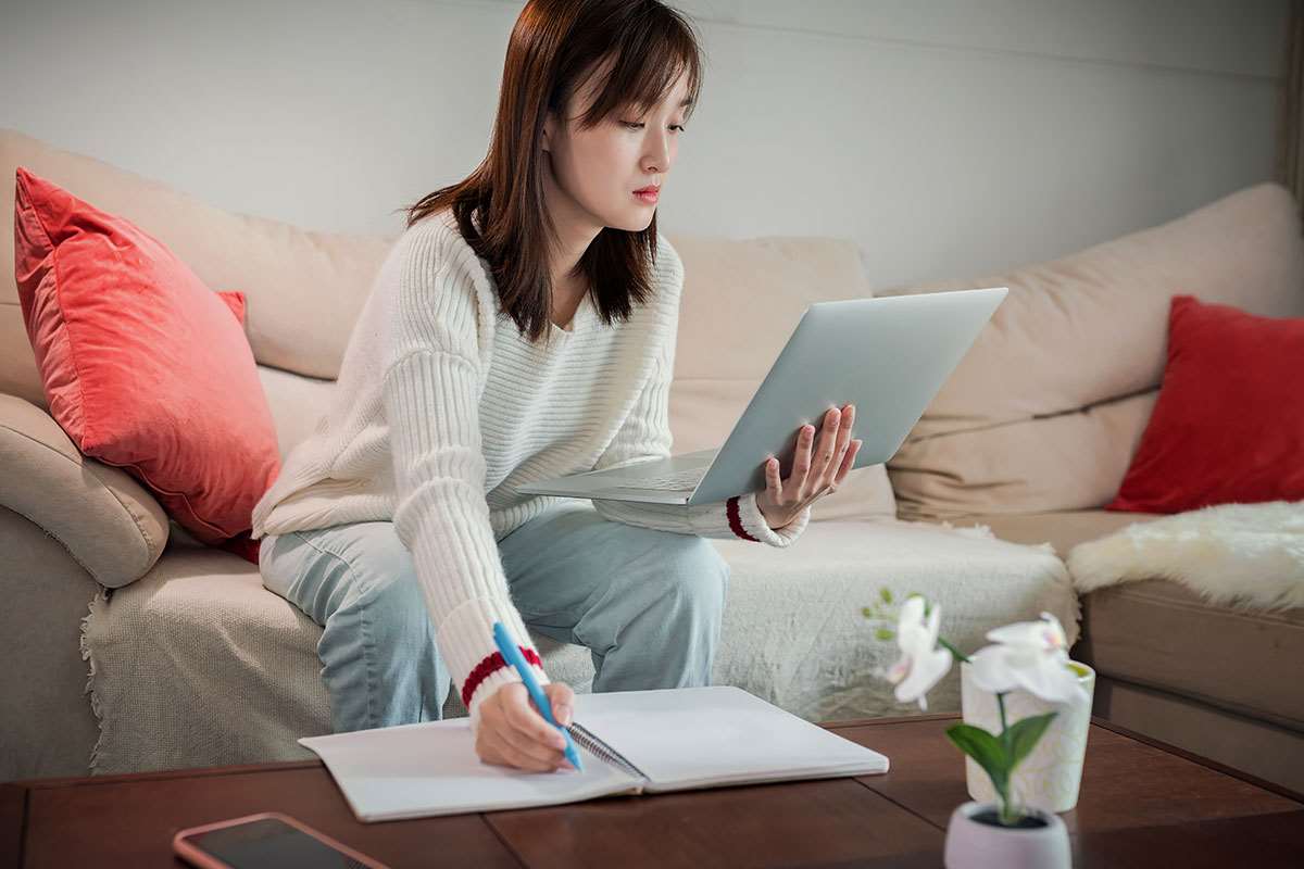 Woman sitting on couch with notes and a computer