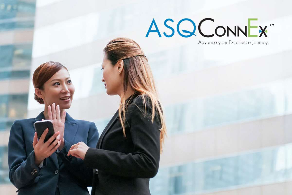 Two women in business attire talk with each other with one woman holding a mobile phone. The ASQConnEx logo is in the top right corner.